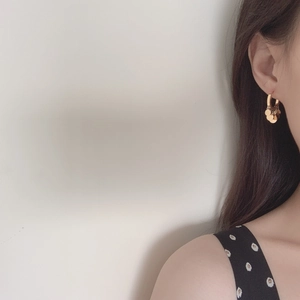 Elegant gold hoop earrings with cascading metal discs shown on model in minimalist style