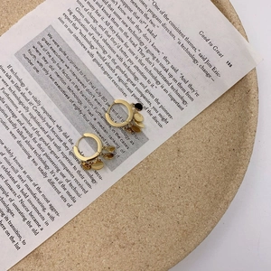 Detail of gold hoop earrings with layered metal disc charms on vintage book pages