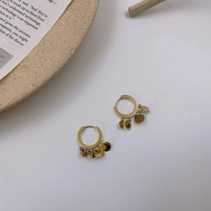 Elegant gold hoop earrings with multiple dangling metal discs on a minimalist background