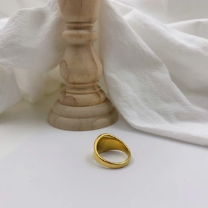 Detailed view of wide gold irregular signet ring on white surface with soft lighting