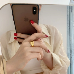Detailed view of a wide gold concave ring with mirror-polished finish on finger