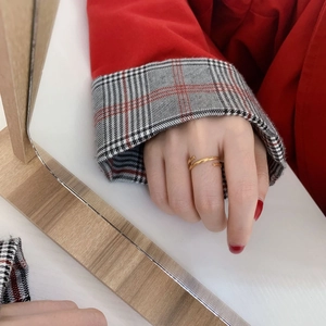 Detail of a minimalist gold layered wrap ring on a model with a red coat background