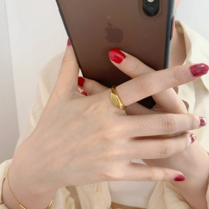 Lifestyle view of a minimalist golden stainless steel ring worn on the index finger