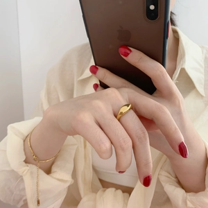 Polished gold wide band ring with matching bracelet shown in a modern lifestyle setting