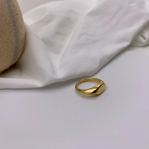 Detailed view of a polished gold geometric signet ring on a white textured background