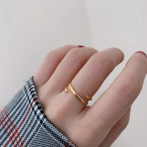 Macro detail of a 18k gold-plated layered wrap ring on a model's finger with a polished finish