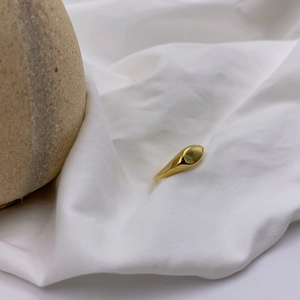 Minimalist gold faceted stainless steel ring featuring a teardrop design on white fabric