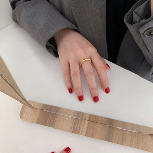 Dettaglio dell'anello a sfere dorate minimalista su sfondo di polsino grigio di classe