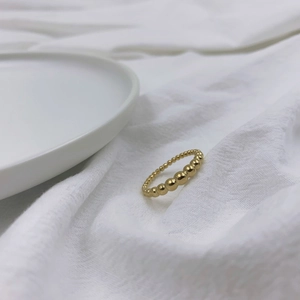 Dettaglio ravvicinato di anello a sfere dorate graduate su tessuto bianco