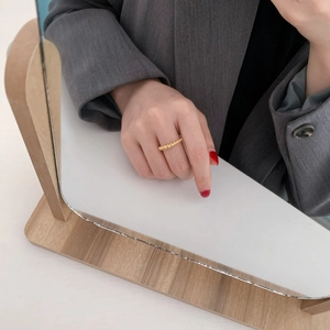 Dettaglio di un anello a sfere dorate minimalista mostrato in un riflesso con stile elegante