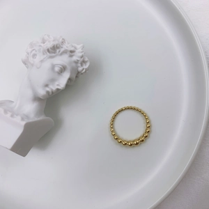 Elegante anello a sfere dorate su vassoio in ceramica con statua di David, minimalista