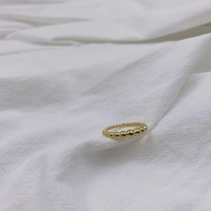 Dettaglio macro dell'anello a sfere dorate con finitura lucida su tessuto bianco