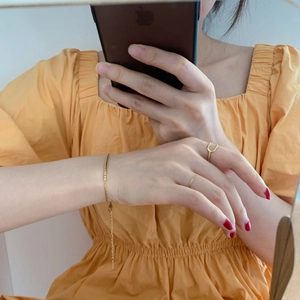Ensemble bracelet chaîne dorée et bagues minimalistes porté en selfie miroir