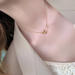 Primo piano della collana a spilla di sicurezza dorata indossata sulla clavicola
