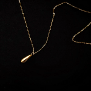 Detail of a minimalist gold teardrop pendant necklace on a premium black background