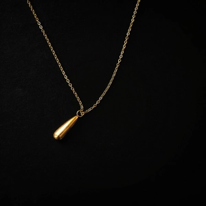 Minimalist gold teardrop pendant necklace with sleek mirror finish on black texture
