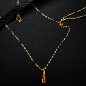 Polished gold water drop pendant necklace on black background with silk ribbon