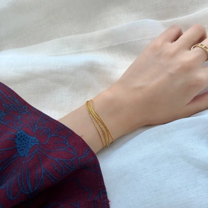 Close-up of minimalist gold layered bracelet and hollow geometric ring on hand