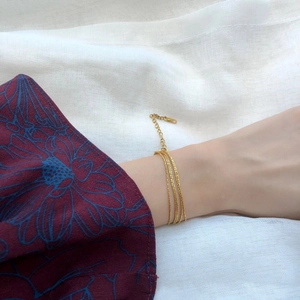 Close-up of triple-layered gold titanium steel bracelet on wrist with linen backdrop