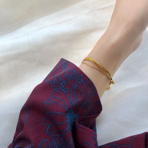 Close-up of minimalist layered gold titanium steel bracelet on wrist with textured chains