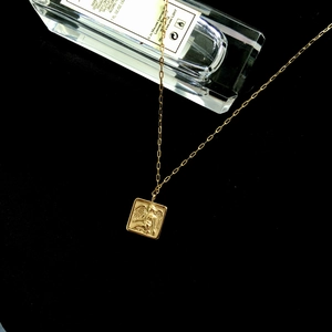 Vue détaillée du pendentif carré en or 18 carats avec gravure d'ange sur fond noir
