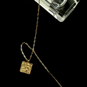 Détail macro du pendentif ange carré en or 18K avec une chaîne à maillons trombone