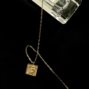 Gros plan du pendentif carré ange en or 18K avec chaîne à maillons rectangulaires