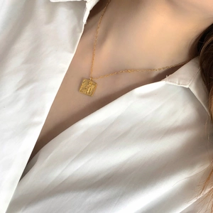Vue détaillée d'un collier plaqué or 18K avec pendentif rectangulaire gravé d'un ange