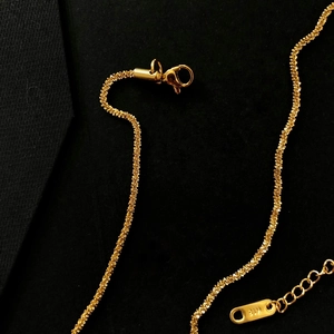 Macro shot of a 18K gold necklace with detailed spiral chain texture and lobster clasp