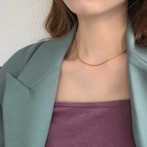 Close-up of a delicate gold snowflake chain necklace layered on a stylish model