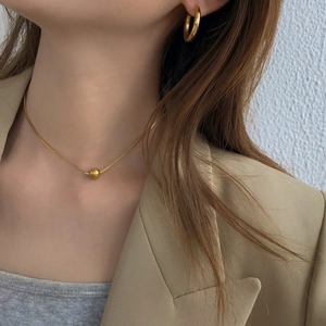 Minimalist gold ball pendant necklace and chunky hoop earrings on a female model