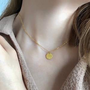 Collana con ciondolo a moneta Evil Eye dorata indossata sulla clavicola