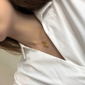 Close-up of polished gold 3D heart pendant necklace worn on a minimalist beaded chain