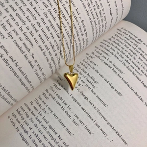Detailed view of polished gold 3D heart pendant necklace on an open book page