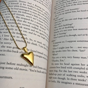 Detail of 3D gold heart pendant necklace with polished finish on a vintage book