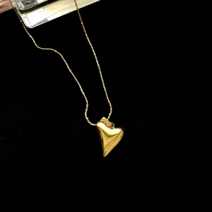 Minimalist gold heart pendant necklace on black velvet with beads and a delicate chain
