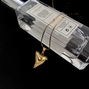 Detailed macro view of a 18K gold triangular pendant on a delicate chain necklace