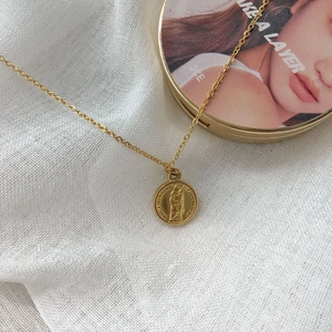 Macro detail of gold coin pendant with portrait relief on elegant white linen fabric