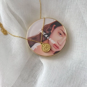 Macro detail of golden coin pendant with floral relief on textured linen backdrop
