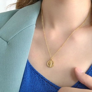 Portrait relief coin pendant necklace in gold-plated finish worn by a model