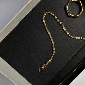 Détail du bracelet chaîne torsadée dorée vintage avec fermoir mousqueton et bague
