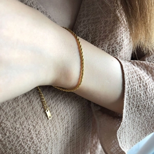 Gros plan d'un bracelet gourmette doré torsadé au poignet avec fermoir réglable