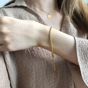 Détail d'un bracelet gourmette dorée torsadée avec une chaîne de rallonge ajustable