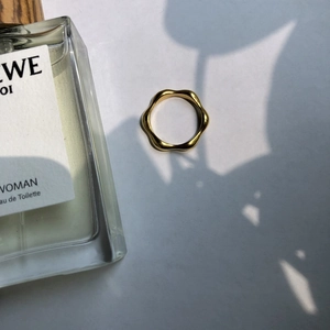 Detailed close-up of a minimalist golden wavy ring featuring a high-polish mirror finish