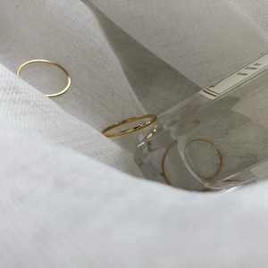 Minimalist stackable gold band rings for women displayed on white textured linen fabric