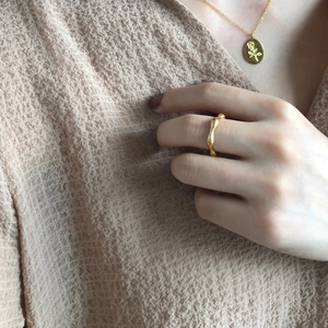 Close-up of elegant gold wavy ring and rose pendant necklace on knit sweater