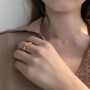 Golden jewelry set featuring sunburst pendant necklace and wavy textured ring on a model
