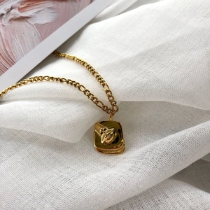 Golden embossed abstract face rectangular pendant necklace on high-quality white fabric