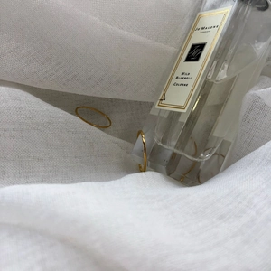 Set of two thin minimalist gold stackable rings displayed on a textured white fabric
