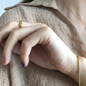 Close-up of stylish wavy gold ring and matching minimalist jewelry set on a model